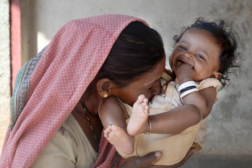 A woman kissing an infant child's stomach in India.