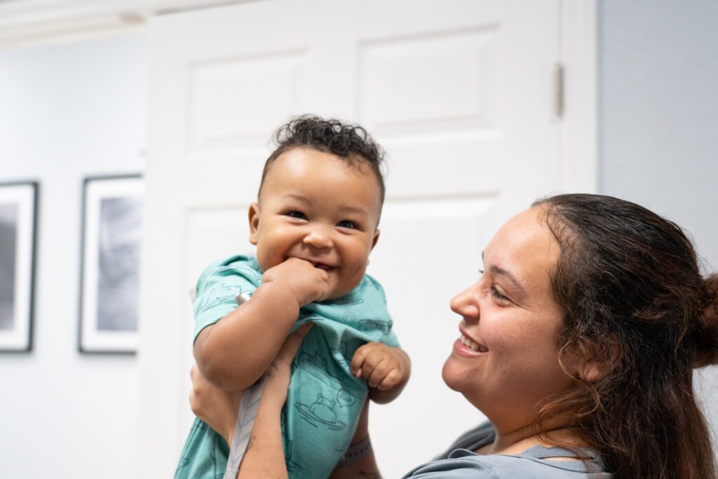 Mother holding up 6-month old child.